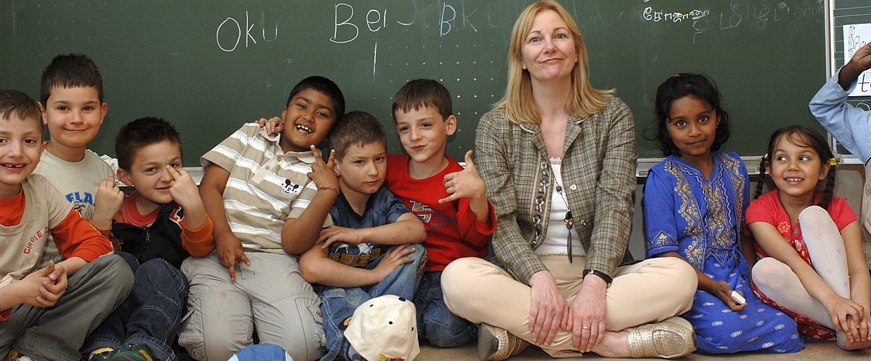 Lehrerin mit Kindern vor einer Tafel
